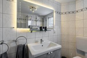 a white bathroom with a sink and a mirror at Ferienwohnung Ankerplatz, 65qm in Sundern +16 photos