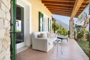a white couch on a patio with a table at Villa Corneghe with pool in Gargnano