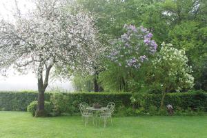 a table and chairs under a tree with flowers at Gîte La Briqueterie 3 Épis in Quesnoy-le-Montant
