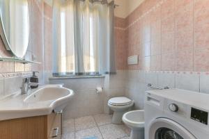 a bathroom with a toilet sink and a washing machine at Appartamenti Marisol in Campo nell'Elba +44 photos