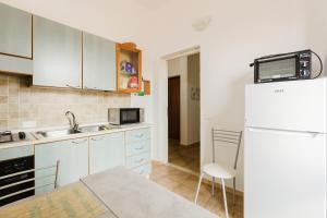 a kitchen with white cabinets and a white refrigerator at Casa Rimedia in Solanas +11 photos