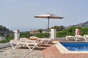a group of chairs and an umbrella next to a pool at Cortijo Los Ángeles Morea in Frigiliana