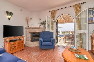 a living room with a blue chair and a television at Cortijo Los Ángeles Morea in Frigiliana