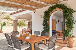 an outdoor dining room with a wooden table and chairs at Cortijo Los Ángeles Morea in Frigiliana