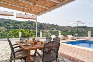 a patio with a table and chairs next to a pool at Cortijo Los Ángeles Morea in Frigiliana