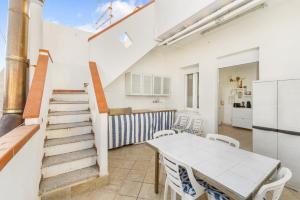 a kitchen and dining room with a table and a staircase at Casa Susanna in Calasetta