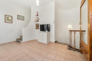 a living room with a television and a tiled floor at Casa Susanna in Calasetta