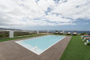 a swimming pool with chairs and the ocean in the background at La Atalaya in Adeje