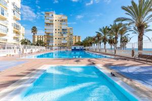 a swimming pool with palm trees and buildings at 50 mts beach with sea views pool in Algarrobo-Costa