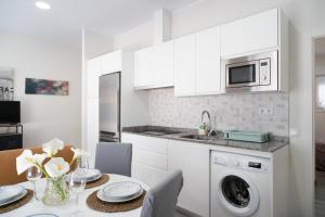 a white kitchen with a table and a microwave at Apartamento Puertu Chicu in Llanes