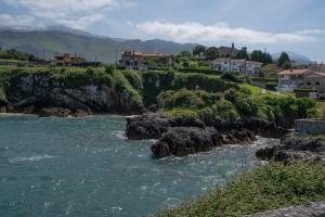 a river with rocks and houses on a mountain at Apartamento Puertu Chicu in Llanes