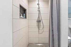 a shower in a bathroom with white tiles at Schmuckstück in Hilzingen +20 photos
