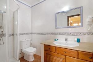 a bathroom with a toilet and a sink and a mirror at Villa Guisado in Albufeira +15 photos