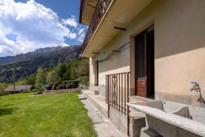 a building with a door and a grassy yard at Il Melo in Trasquera