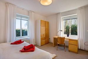 a bedroom with a bed and a desk and windows at Voßberg großes Ferienhaus in Grömitz