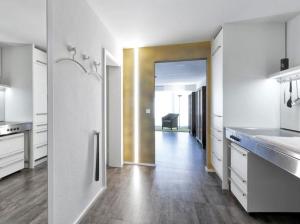 a kitchen with white cabinets and a hallway with a chair at Hochburger 21 in Emmendingen