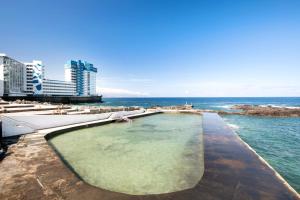 a swimming pool on the beach next to the ocean at La Carpinteria in Tacoronte