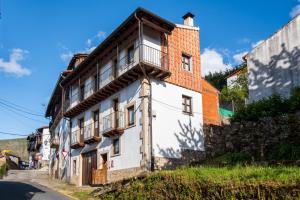 a white building with a balcony on the side of a street at Las Puentes 1 in Candelario