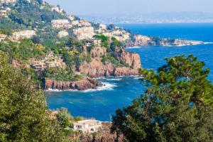 a group of houses on top of a hill next to the ocean at Duplex 2 chambres Golden Sun in Théoule-sur-Mer