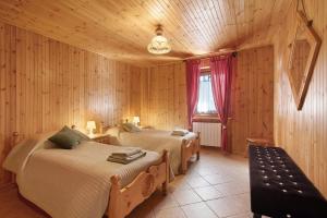 a bedroom with two beds and a bench in it at La Maison du Bonheur Lillaz in Cogne