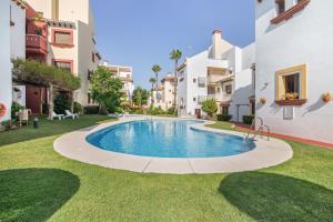 a swimming pool in the middle of a yard with buildings at Saadia Golf in Huelva