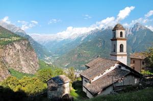 a church on a hill with mountains in the background at Sweet Somma Mountain Lodge 2 in San Guglielmo
