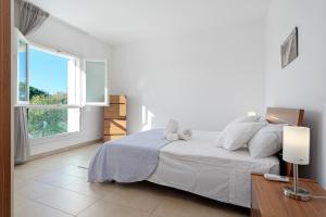 a white bedroom with a bed and a window at Villa Marconi Apartment 7 in Golfo Aranci