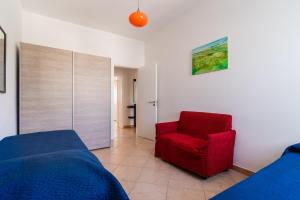 a bedroom with a bed and a red chair at Villa Tina a Torre Lapillo in Torre Lapillo