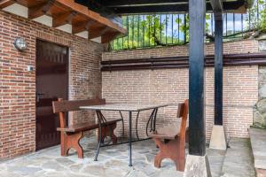a table and a bench next to a brick wall at Quintanal de Villacarriedo in Villacarriedo