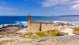 a church on the rocks next to the ocean at Casa Muxía Mar y montaña in Muxia