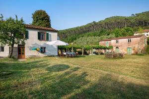 a house with a table and an umbrella in a yard at Tuscany Charme Coselli Restored in Capannori