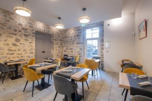 ein Restaurant mit Tischen und Stühlen und einer Backsteinmauer in der Unterkunft Chatus in Ruoms