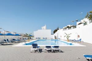 a swimming pool with two chairs and a swimming poolvisorvisor at Casa Noria in Vejer de la Frontera