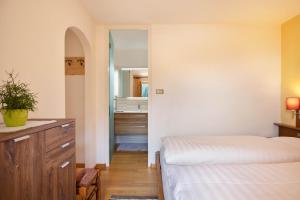 a bedroom with a bed and a dresser and a bathroom at Appartements Gabrielli Anna in Trodena