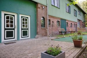 a green building with a door and a patio at Ferienwohnung Junge 4 in Lohe-Rickelshof