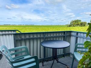 a table and chairs on a balcony with a view of a field at Relas Ferienwohnungen - Spatzennest in Nordstrand