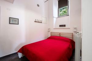 a red bed in a white room with a red blanket at Al Cornelio in Orvieto