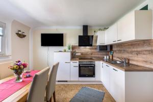 a kitchen with white cabinets and a table with a vase of flowers at Baumelt Ferienwohnung in Hechingen