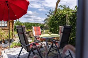 a patio with a table and chairs and a red umbrella at Baumelt Ferienwohnung in Hechingen