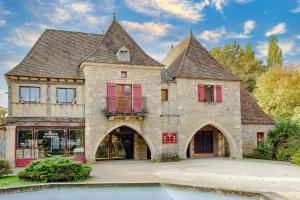 a large brick building with red shuttered windows at Lumineux Le Bugue in Le Bugue