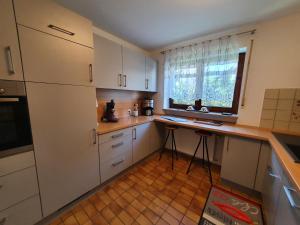 a kitchen with white cabinets and a counter with a window at Stadler in Langenargen +12 photos