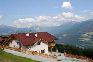 a house on a hill with mountains in the background at Mitterhof in Villandro
