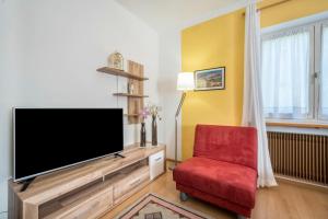 a living room with a flat screen tv and a red chair at Apartement Oase in Lana