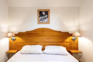 a bedroom with a wooden bed with two white pillows at Appartement Atlas in Albiez-Montrond