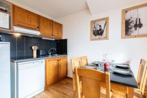 a kitchen with a table and chairs and a kitchen with a refrigerator at Appartement Atlas in Albiez-Montrond