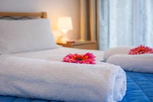 two white beds with towels and red flowers on them at 32sq Apartment with Balcony in Vlachopoulátika