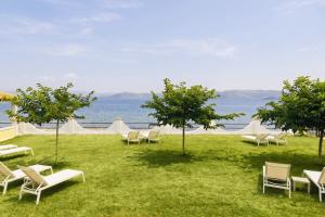 a group of chairs sitting on the grass near the water at Kamini Apartments in Kavos