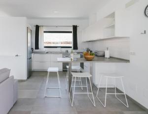 a kitchen with white cabinets and white stools at Casa Agua Nueva 53 in Frontera