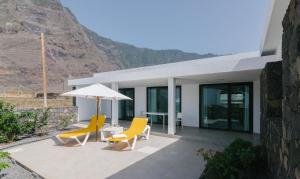 a patio with two yellow chairs and an umbrella at Casa Agua Nueva 53 in Frontera