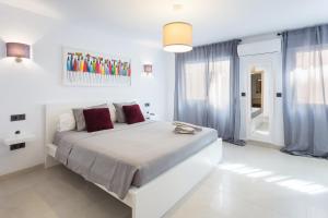 a white bedroom with a large bed with red pillows at Lujoso cerca de playa in Jávea